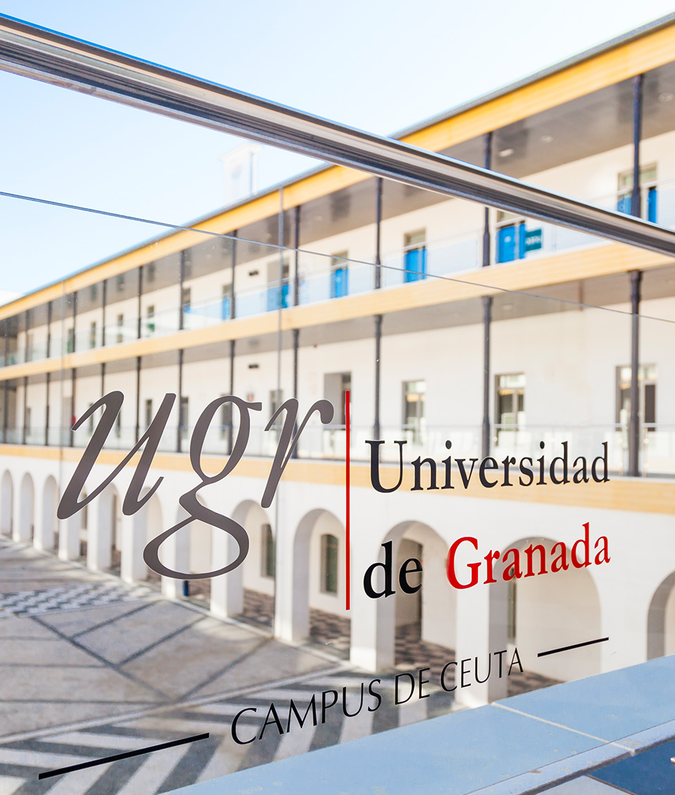 Detalle vinilo con el logo de la UGR sobre baranda de cristal en el patio interior de la Facultad de Educación, Economía y Tecnología de Ceuta